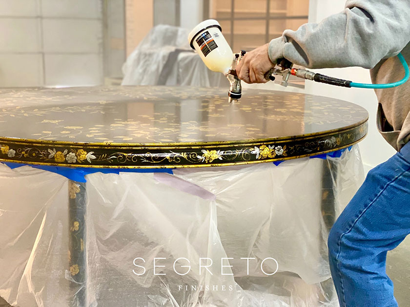 embellishing top of custom painted black table with gold leaves