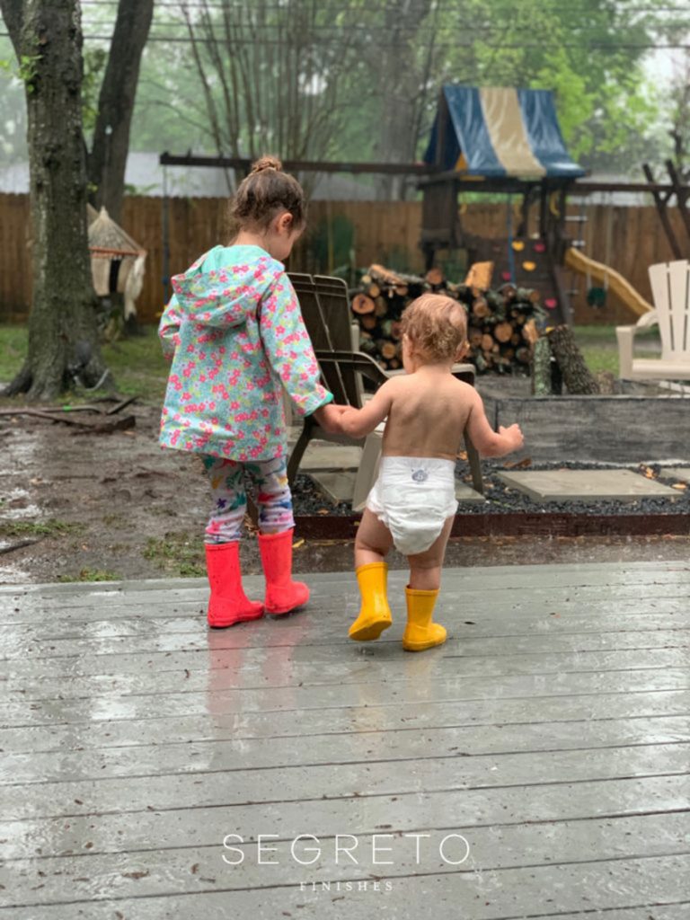 girl and baby walking in backyard