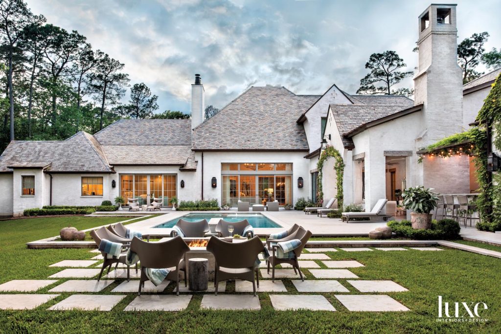 Architect Ken Newberry maintained the largest portion of the lot possible for outdoor living and wrapped the architecture around it. Janus et Cie Amari rattan armchairs surround a fire pit overlooking landscaping designed in collaboration with landscape designer Serena Gibson and installed by Kainer & Kainer Landscape Architecture. Cameron Builders, Inc. installed the pool and hardscaping.