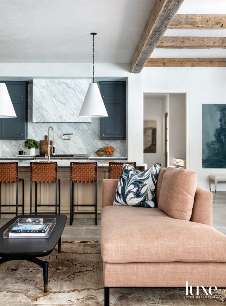 An eye-catching pillow in Rule of Three’s Stone Plum Starlight Night fabric from James contrasts the Holland & Sherry linen-clad breakfast room sofa near a coffee table from Area. The adjacent kitchen’s Rose Uniacke pendants light Mark Albrecht Studio counter stools from Holly Hunt. The large painting by Jessica Halonen is from M. Naeve.