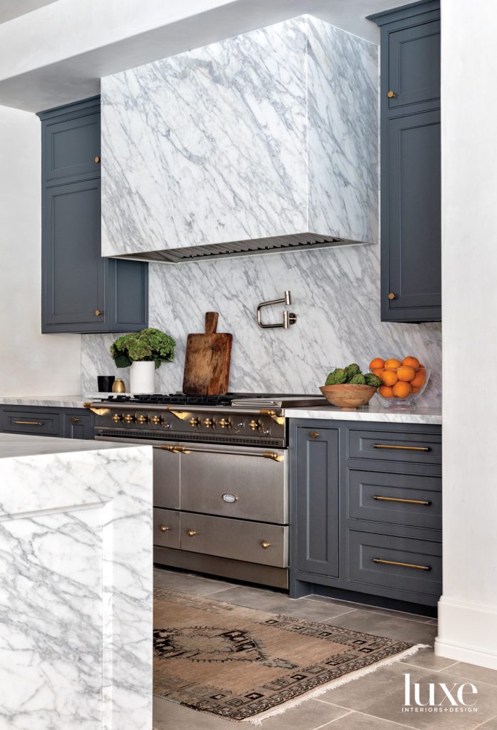 The kitchen’s Calacatta marble vent hood and backsplash from Walker Zanger frame a Lacanche gas range. The rug is from Carol Piper Rugs.