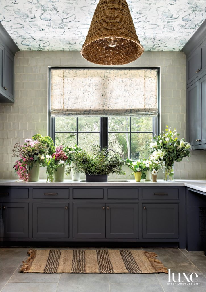Eskayel wallpaper from Supply stars on the ceiling in this laundry room, which features an Arcilla field tile backsplash from Ann Sacks, cabinetry painted Sherwin-Williams Cityscape and quartzite counters from Arizona Tile. A rattan pendant from Found and rug from Kuhl-Linscomb add warmth.