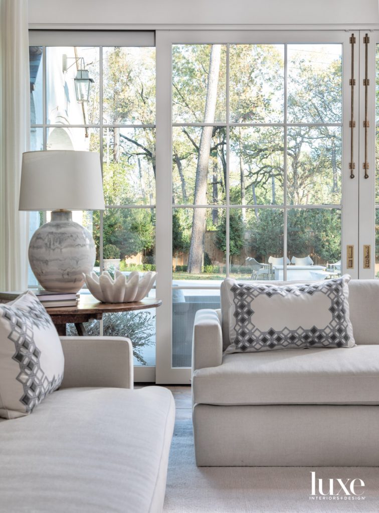 The living room’s custom Belgian-style sofas in Holly Hunt fabric are accented with pillows in a Holland & Sherry custom-embroidered material. Interior designer Sheri Bailey chose a hand-blown lamp with a marble finish from Longoria Collection to top an antique walnut table from Liz Spradling Antiques.