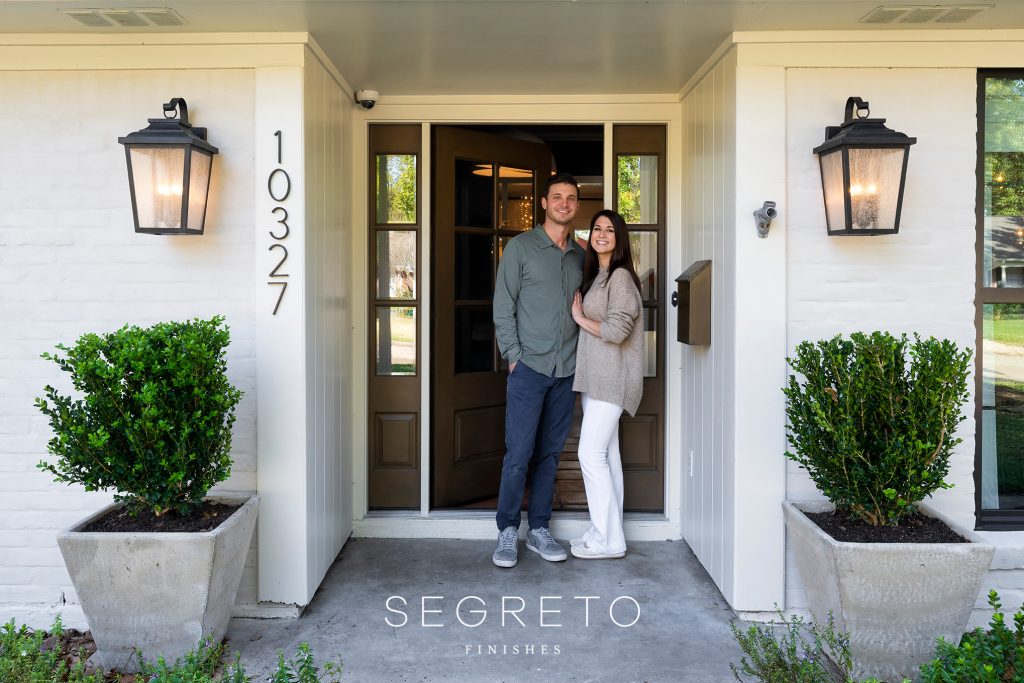 Happy couple standing in front of their home.